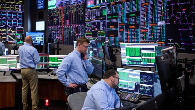 A busy trading floor with multiple screens displaying market data and professionals engaged in analysis and communication.