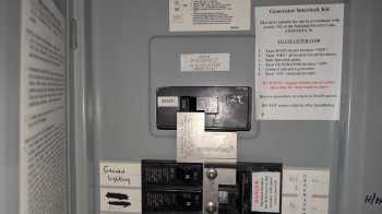 A close-up view of a residential circuit breaker panel with labels and instructions for generator interlock use.