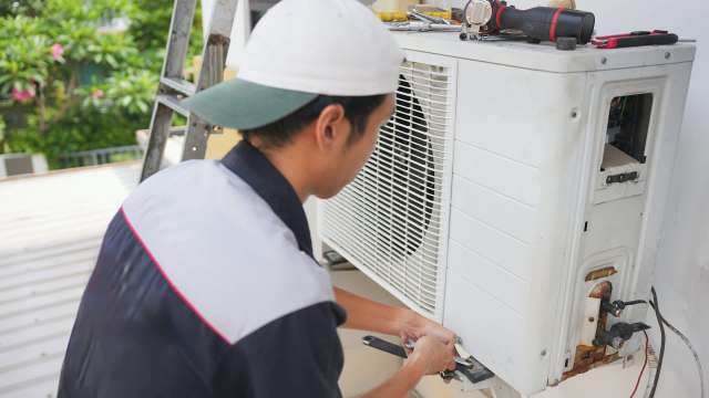 A technician repairs an air conditioning unit.