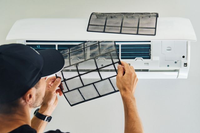 A maintenance man is cleaning the filters in an AC.