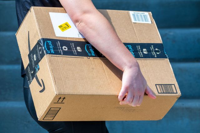 A person carrying a cardboard Amazon Prime box.