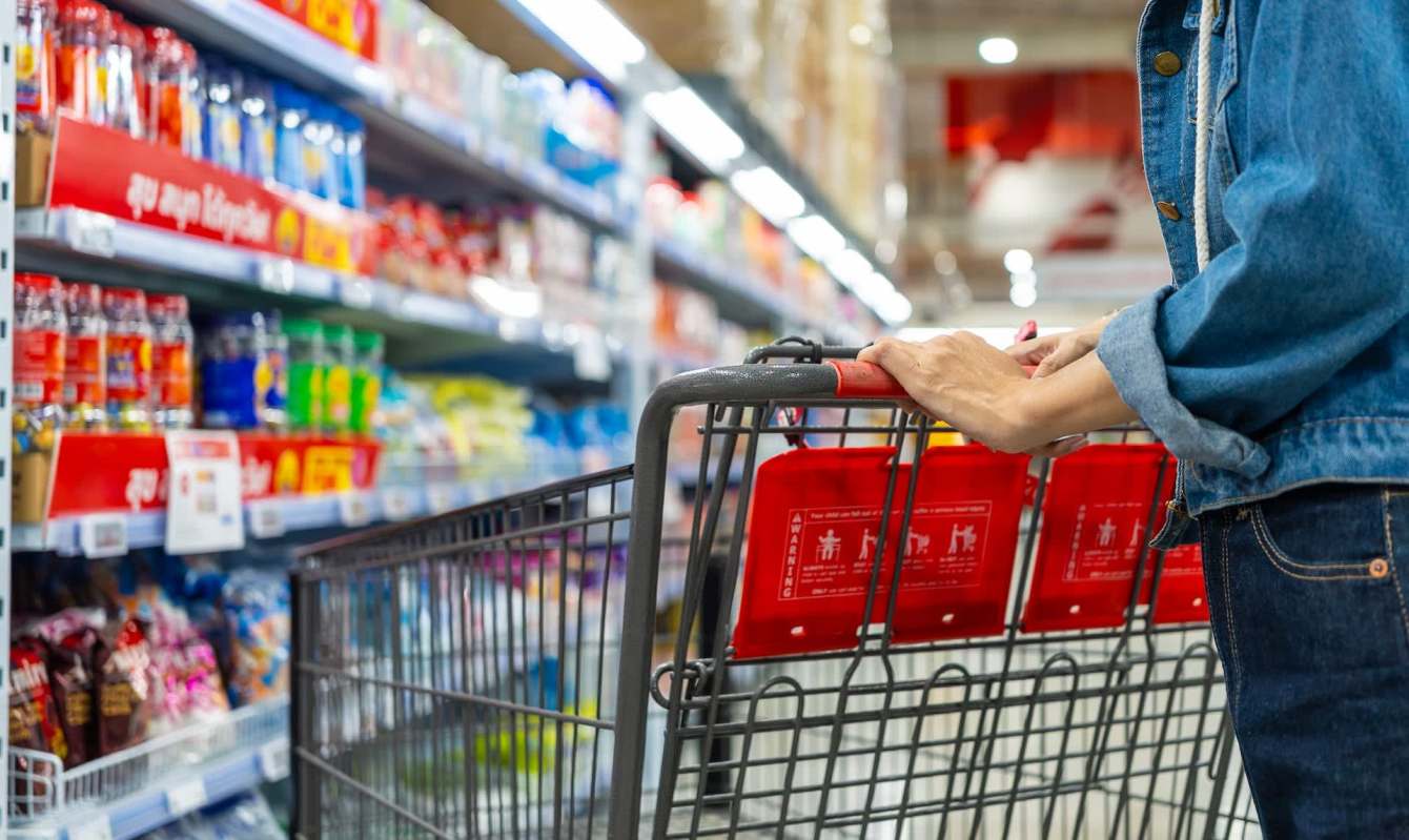 A shopper pushing a cart in a grocery store.