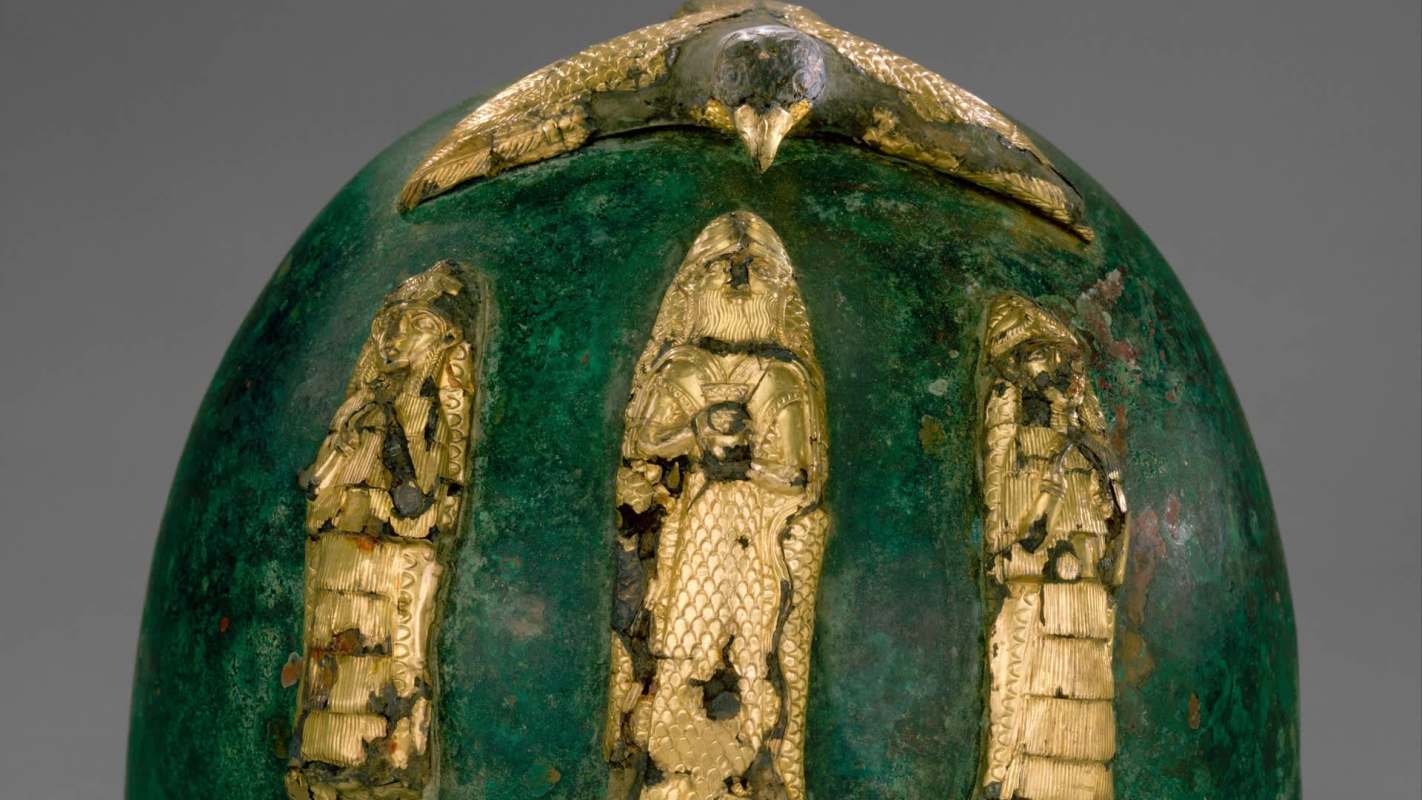 A decorative green egg adorned with gold figures and a bird on top, showcasing ancient craftsmanship.
