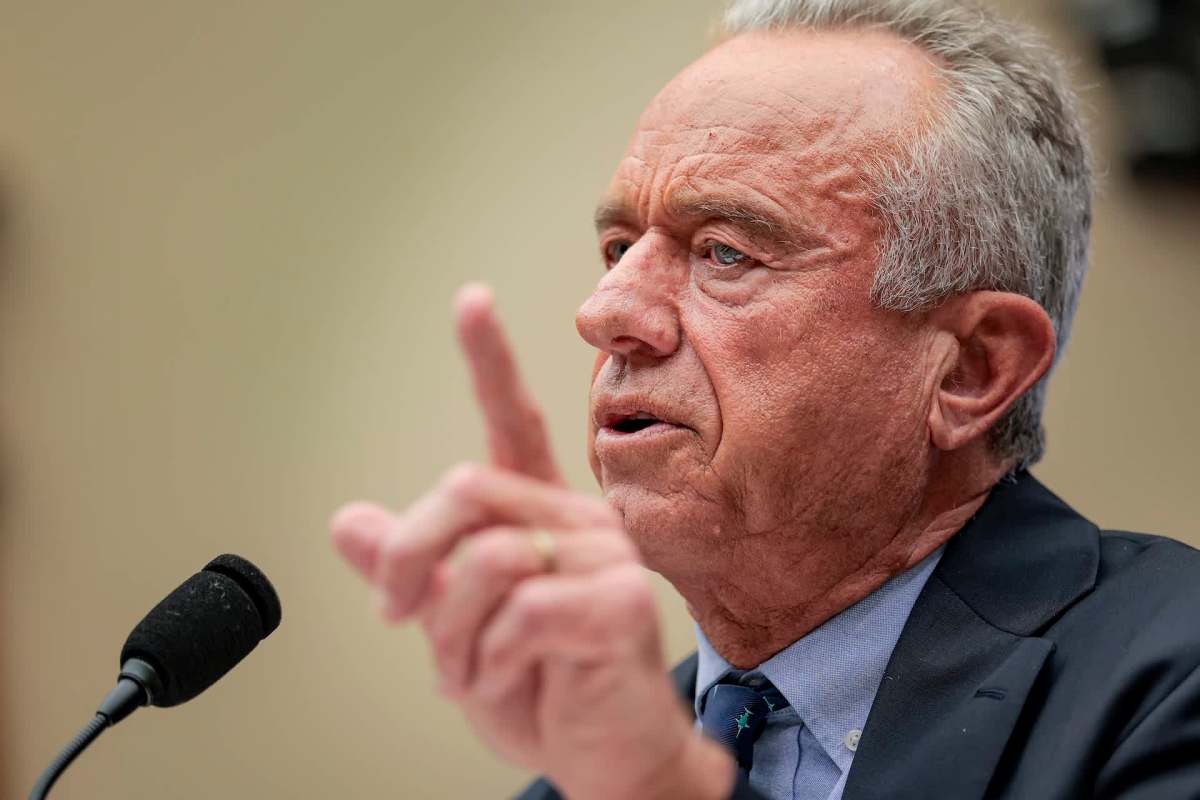 Robert F. Kennedy Jr. gestures emphatically while speaking into a microphone during a formal setting.