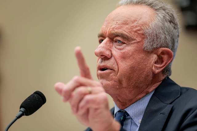 Robert F. Kennedy Jr. gestures emphatically while speaking into a microphone during a formal setting.