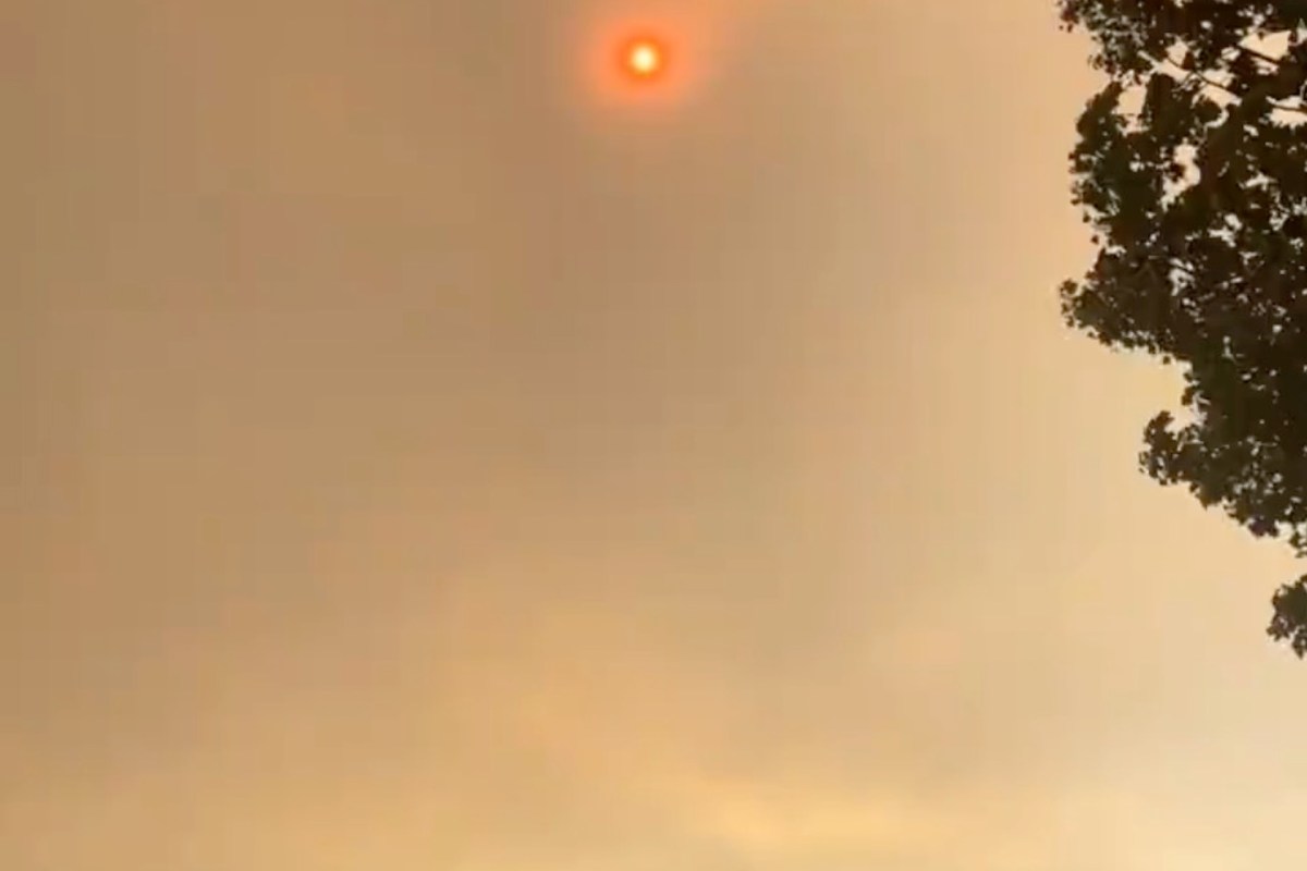 A smoky sky with a faint red sun peeking through, partially obscured by haze.
