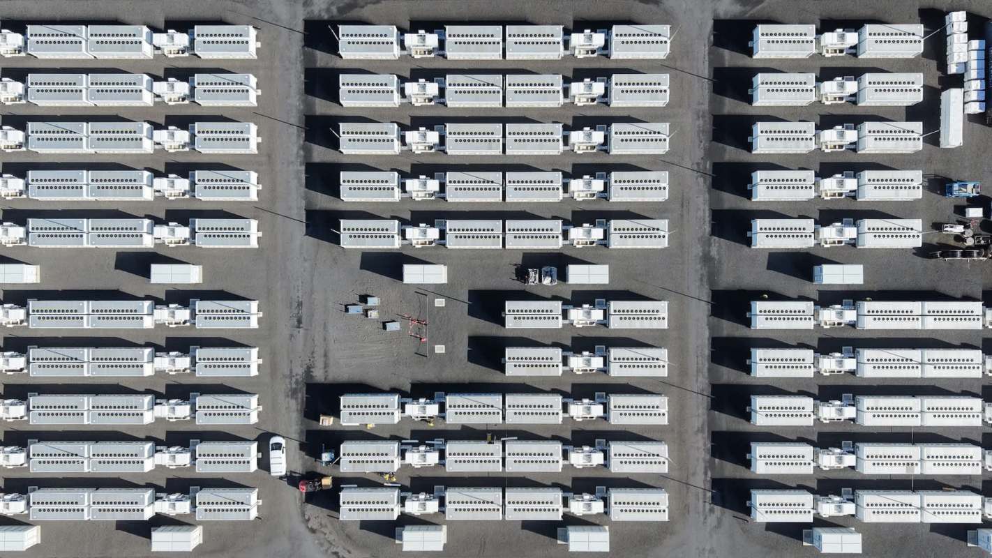 An aerial view of a large area filled with white shipping containers arranged in rows that form a data center campus.