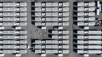 An aerial view of a large area filled with white shipping containers arranged in rows that form a data center campus.