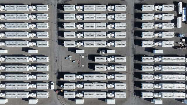 An aerial view of a large area filled with white shipping containers arranged in rows that form a data center campus.