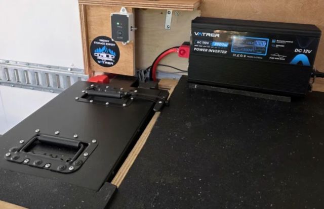 A power inverter and energy storage unit are mounted on a work surface with a control panel and wiring.