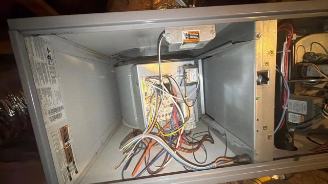 An open electrical panel showing various wires and components inside a gray housing unit.