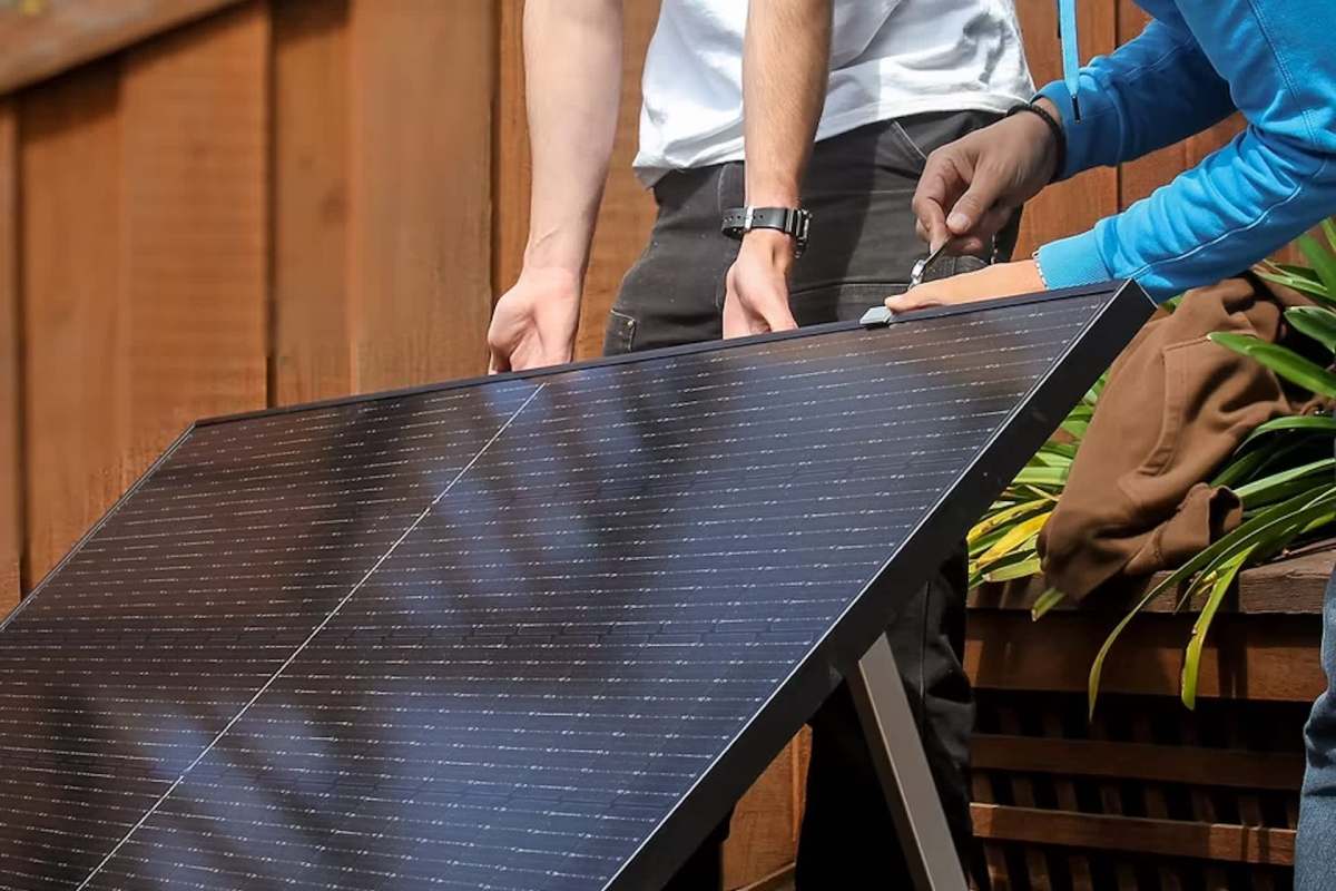 Two people putting a solar panel on a mount.