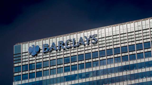 The Barclays logo on a modern glass building against a dark sky.