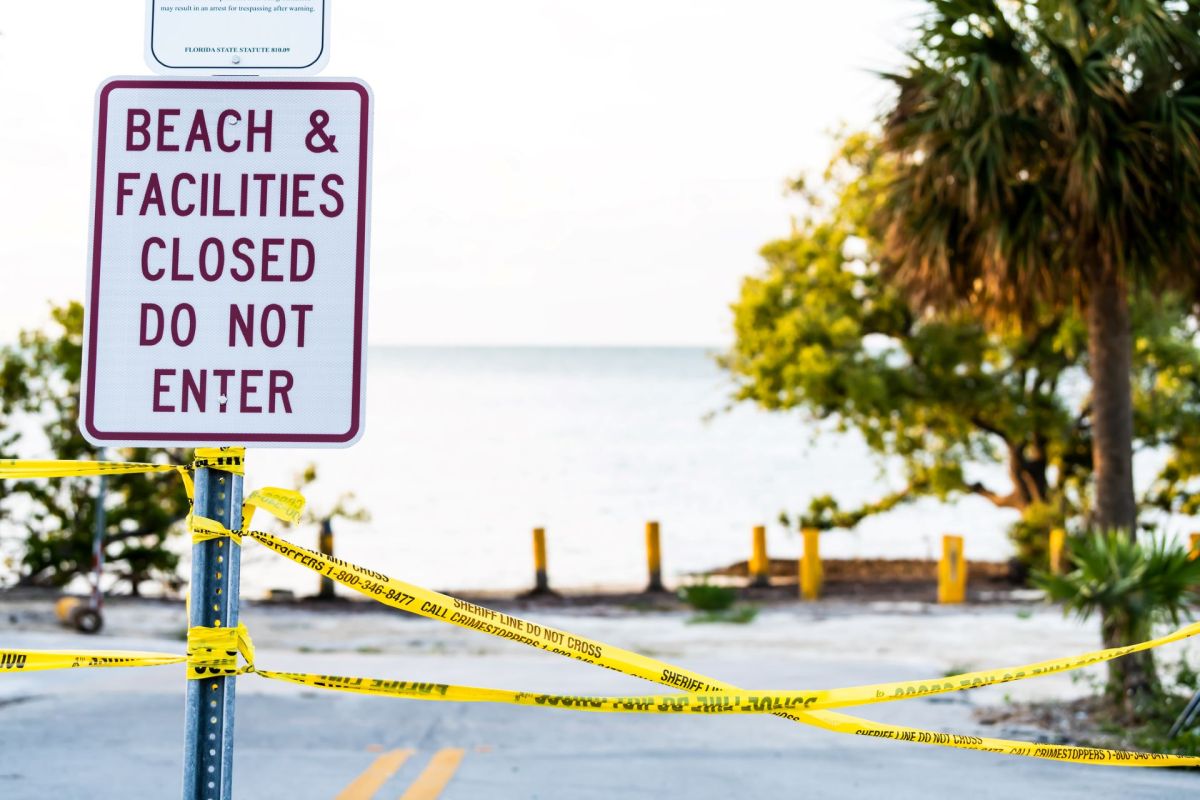 A closed beach sign with caution tape.