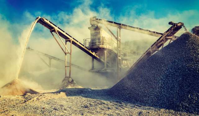 A gravel processing site with machinery operating amid dust, conveyor belts transporting materials, and large piles of gravel.