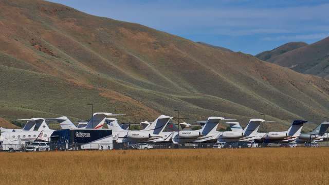 A line of private jets parked in front of mountains.