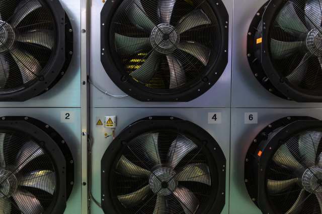 Industrial fans numbered and mounted on a wall.