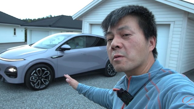 Bjørn Nyland points toward a silver XPeng G6 Performance electric vehicle.