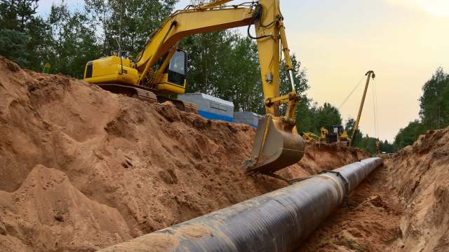 An excavator digging a trench for a pipeline.