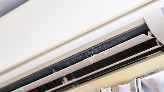 Close-up of an air conditioner unit with water droplets forming and dripping from the internal section.