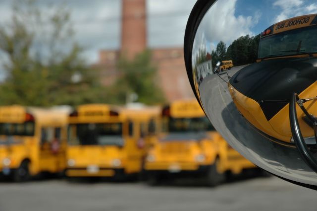 A school bus mirror reflecting other yellow school buses.