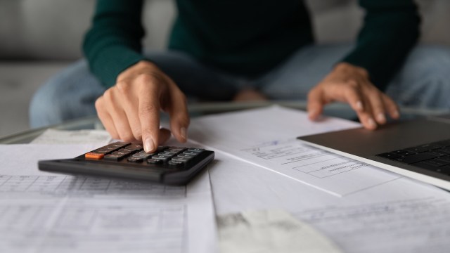 A person uses a calculator while reviewing paperwork.