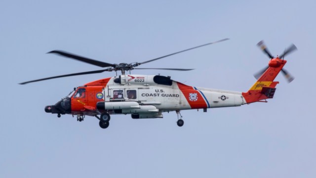A U.S. Coast Guard helicopter flying in a clear sky.
