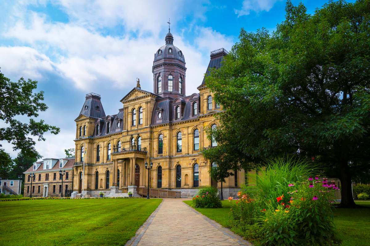 A historic building featuring ornate architecture, surrounded by lush green grass and colorful flower beds.
