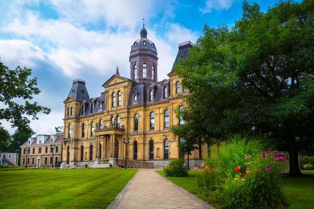 A historic building featuring ornate architecture, surrounded by lush green grass and colorful flower beds.