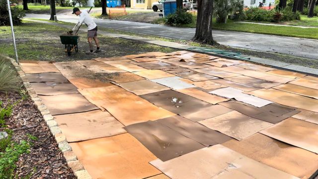A man putting mulch over cardboard.