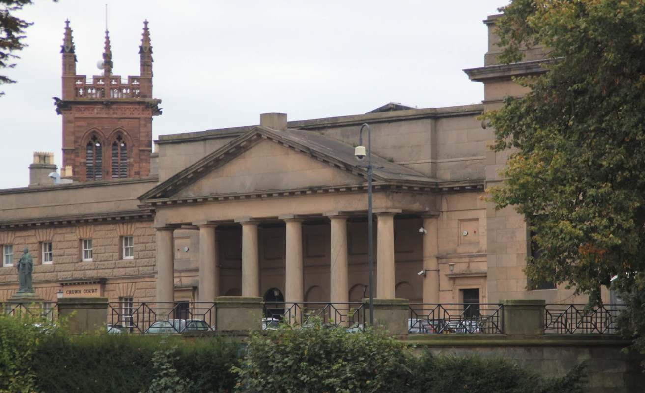 A historic building featuring classical architecture with columns and a bell tower in the background.