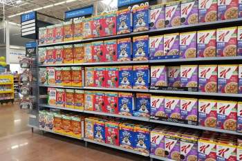 A grocery store aisle filled with various brands of cereal boxes on display.