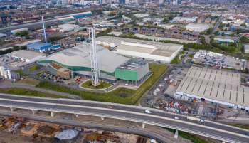 An overhead view of industrial buildings, a highway, and surrounding urban areas.