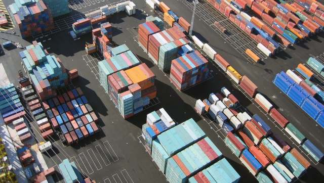 Aerial view of a shipping container yard with stacked containers in various colors and arranged on a paved lot.