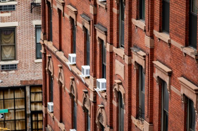 An apartment building with multiple window AC units.
