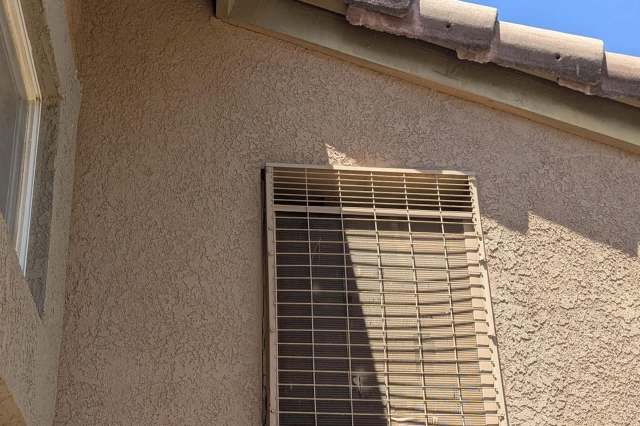 A window with a metal security screen on the exterior wall of a house.