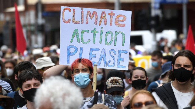 A protestor holding a sign reading "Climate Action Please."