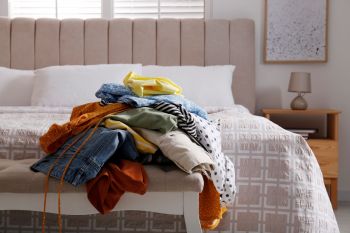 A pile of clothes near a bed.