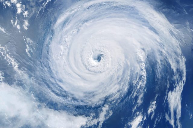 A satellite image of a powerful hurricane swirling over the ocean with a well-defined eye at its center.