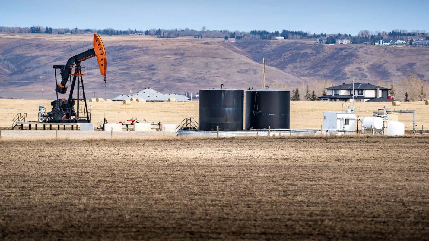 An oil well site near houses in a rural area.