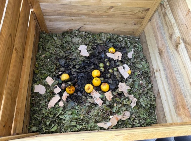A pile of differently coloured compost in a wooden container.