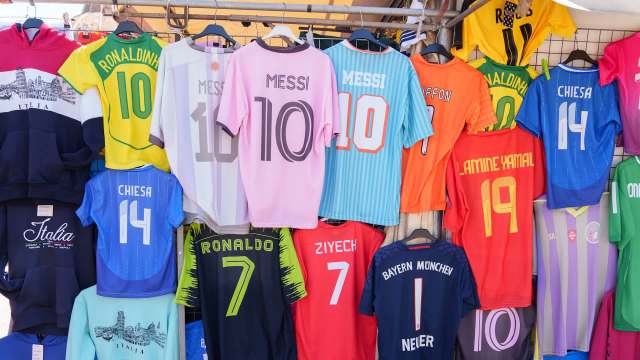 A colorful display of various soccer jerseys featuring famous players and teams, arranged on hangers.