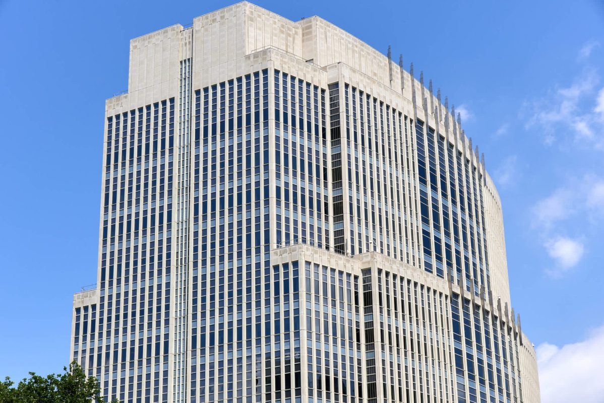 A modern skyscraper with a glass facade against a clear blue sky.