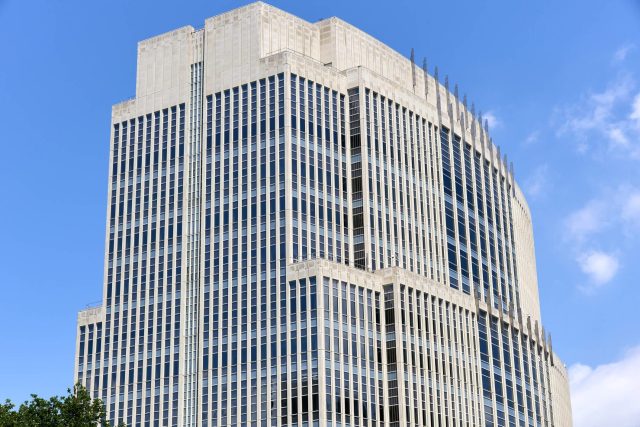 A modern skyscraper with a glass facade against a clear blue sky.