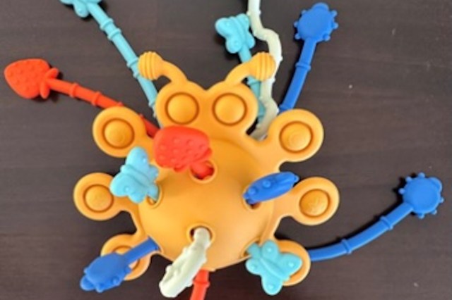 A colorful toy with multiple arms featuring butterflies and fruits.