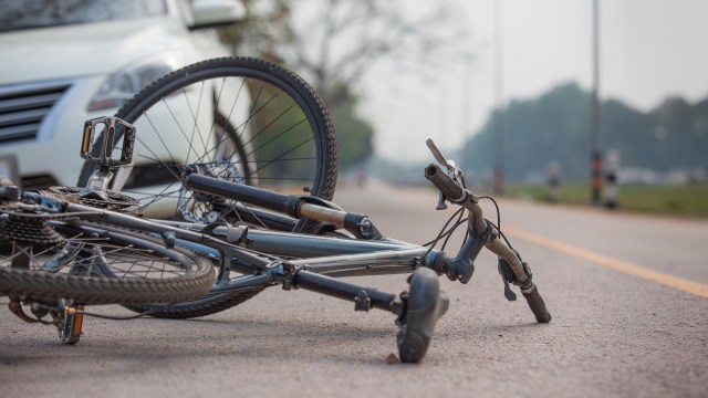 A fallen bicycle in front of a car.