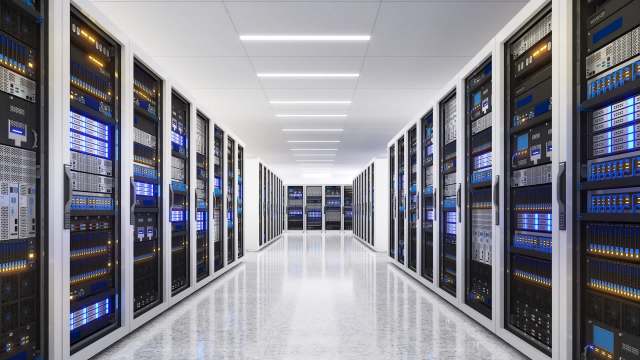 A row of server racks in a data center illuminated by blue and white lights.