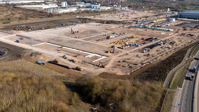 An aerial view of a large construction site with machinery and marked areas for future development.