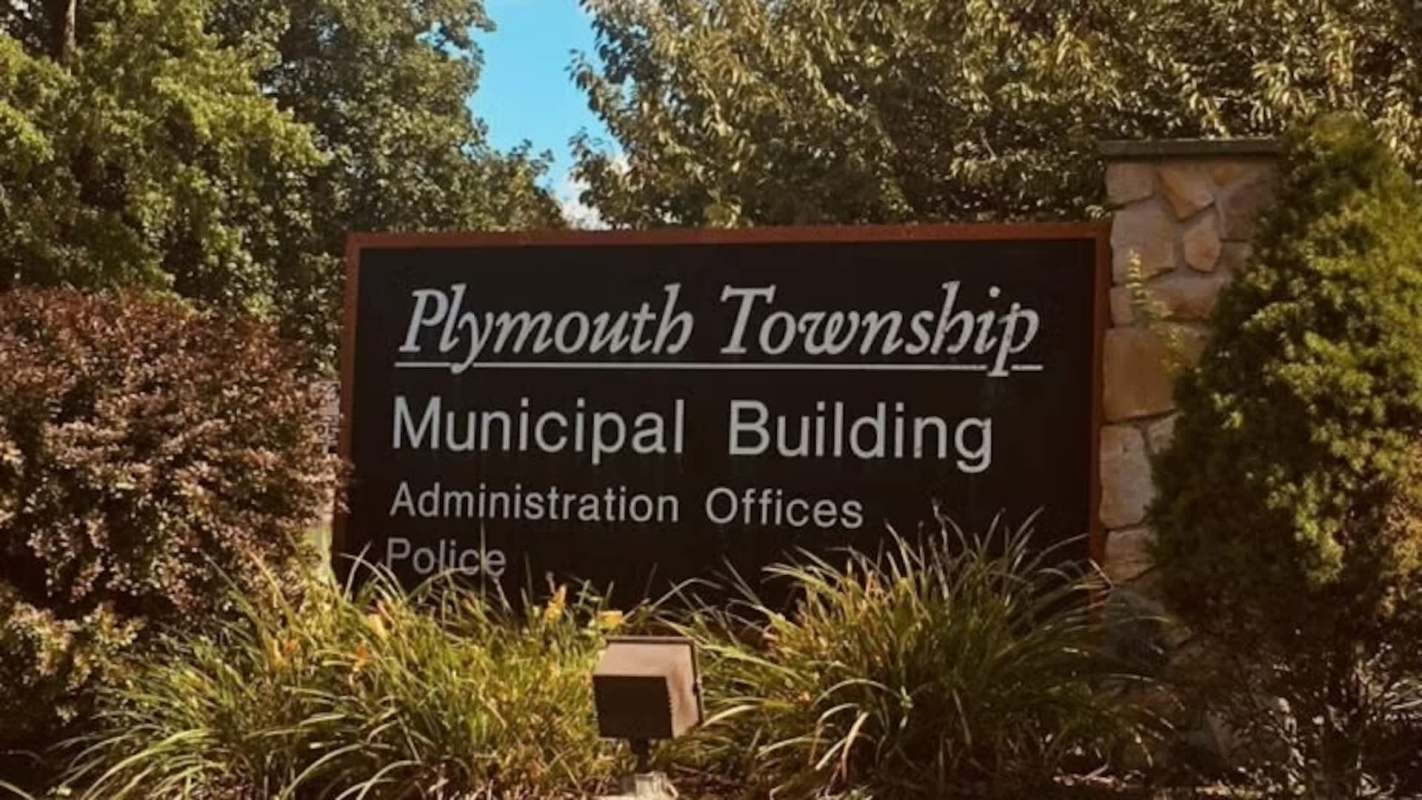 A sign for Plymouth Township Municipal Building surrounded by greenery.