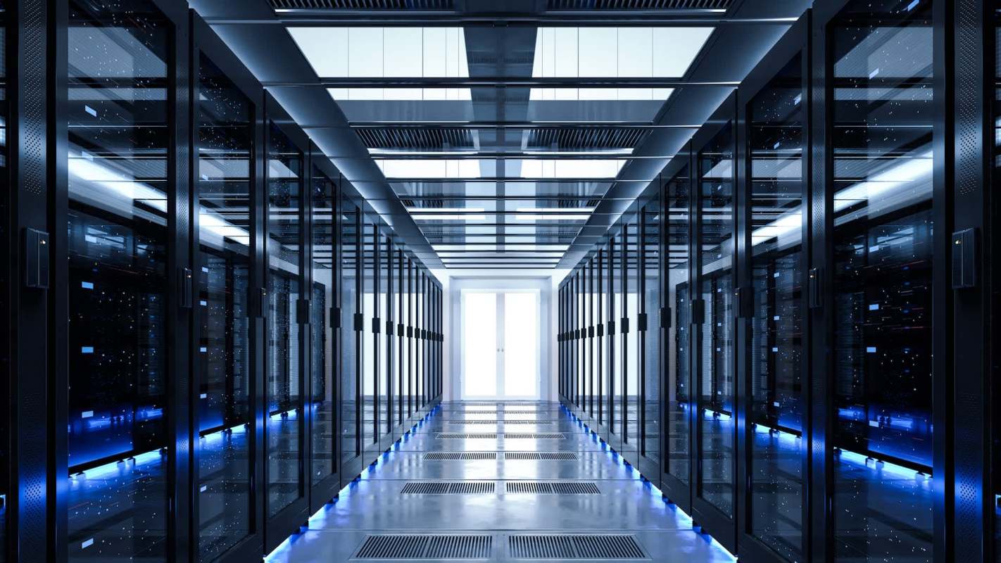 A modern data center hallway lined with black server racks and illuminated by blue lighting.